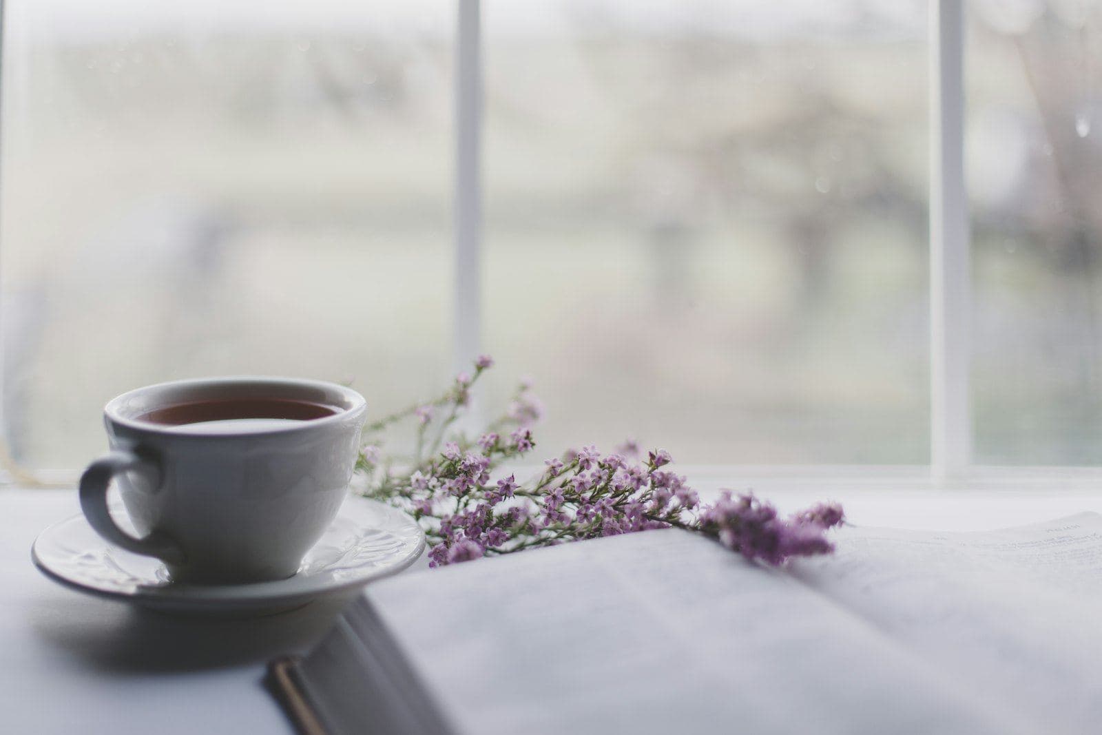 A cup of tea on a table beside a bright window
