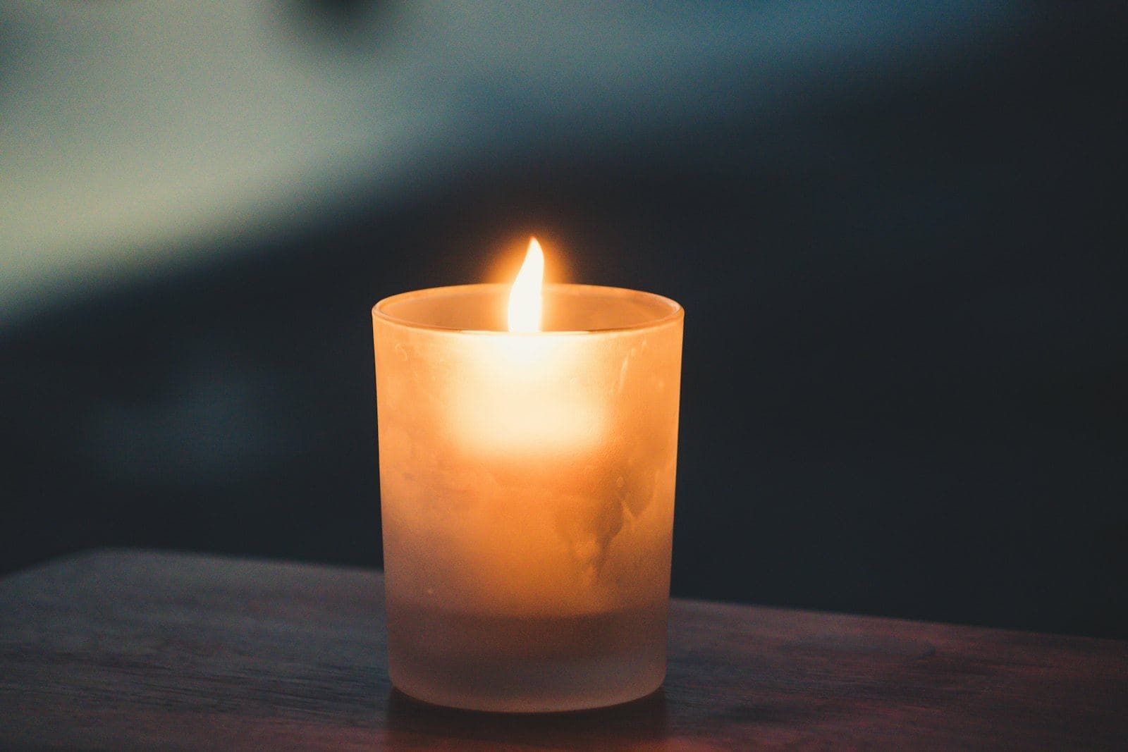 A single lit candle in a glass holder