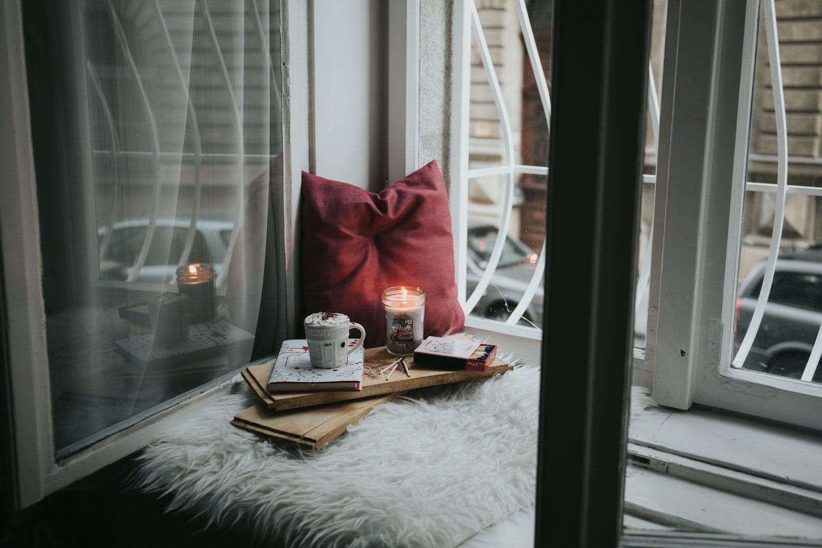 A cozy window seat with a lit candle and a cup of tea