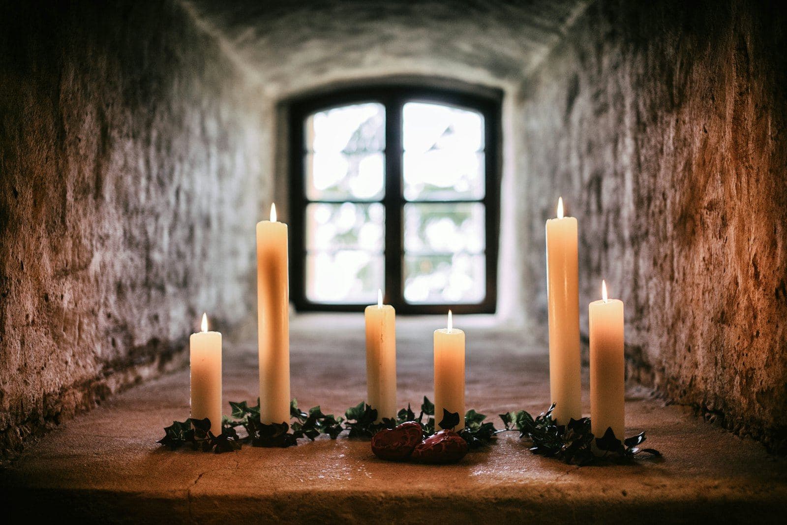Candles glowing on a table beneath a small window