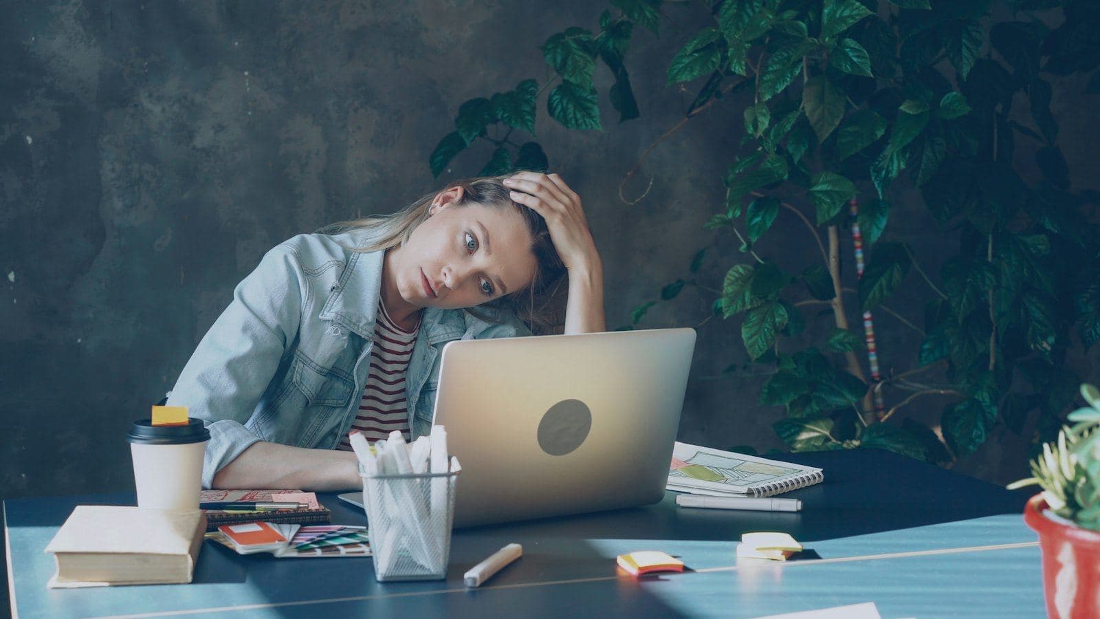 A woman at her desk resting her head on her hand, tired after a long day