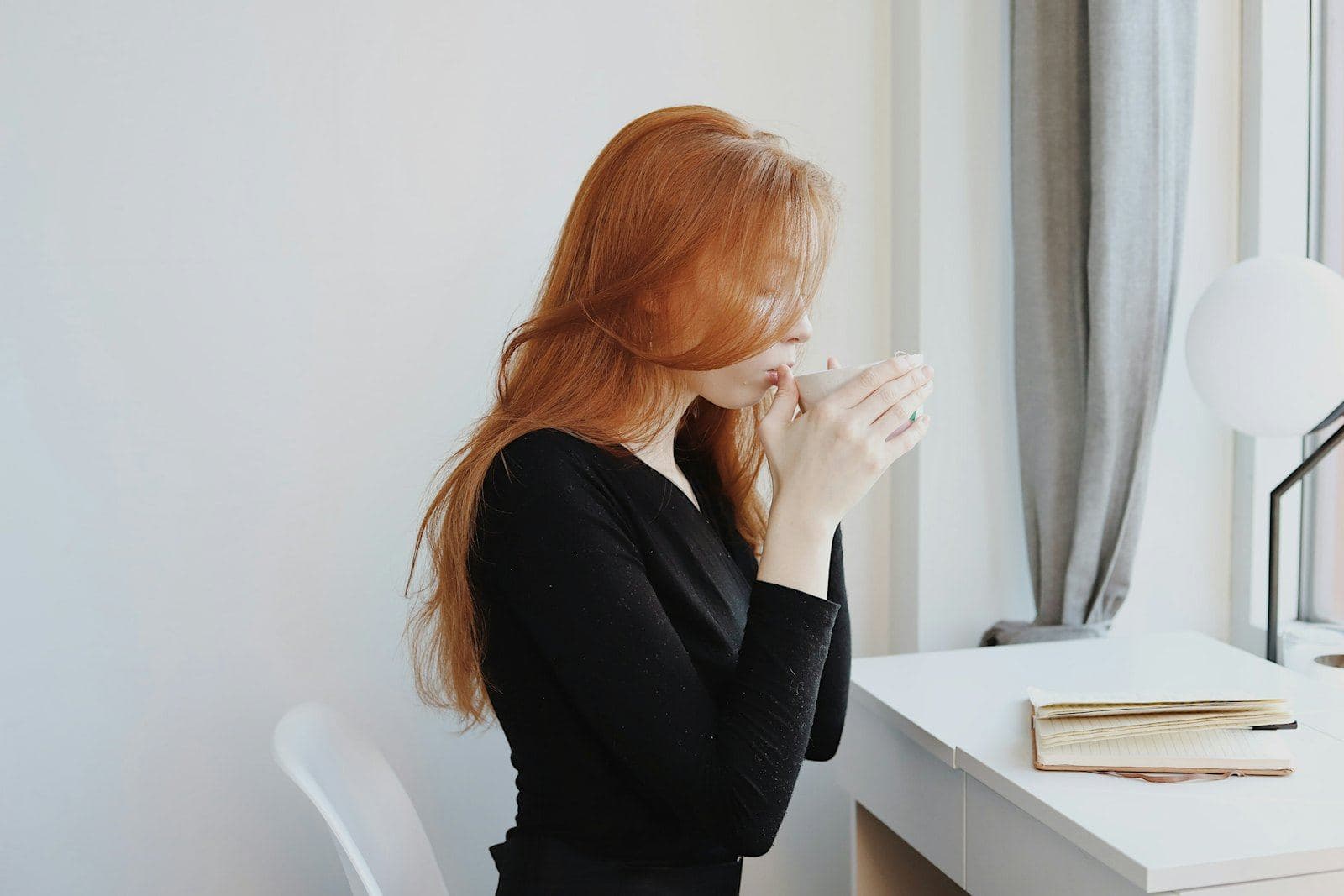 A woman holding a warm cup by a bright window