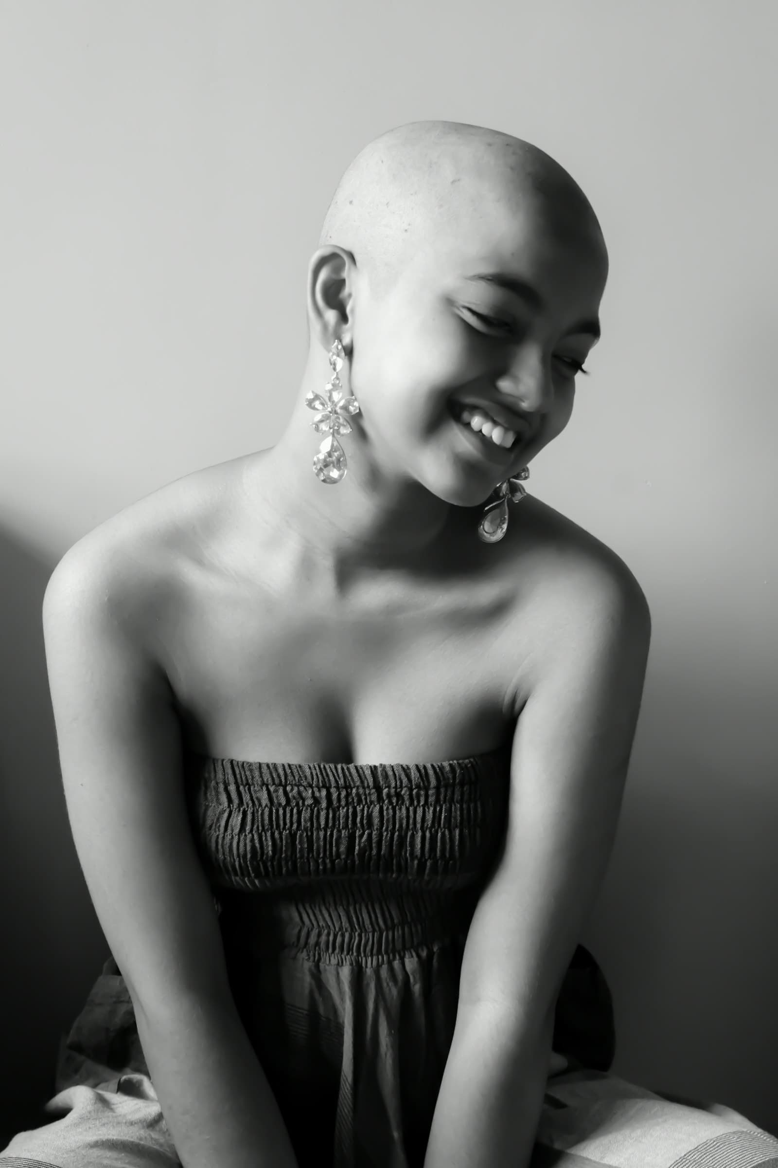 A smiling woman with a shaved head in a black-and-white portrait