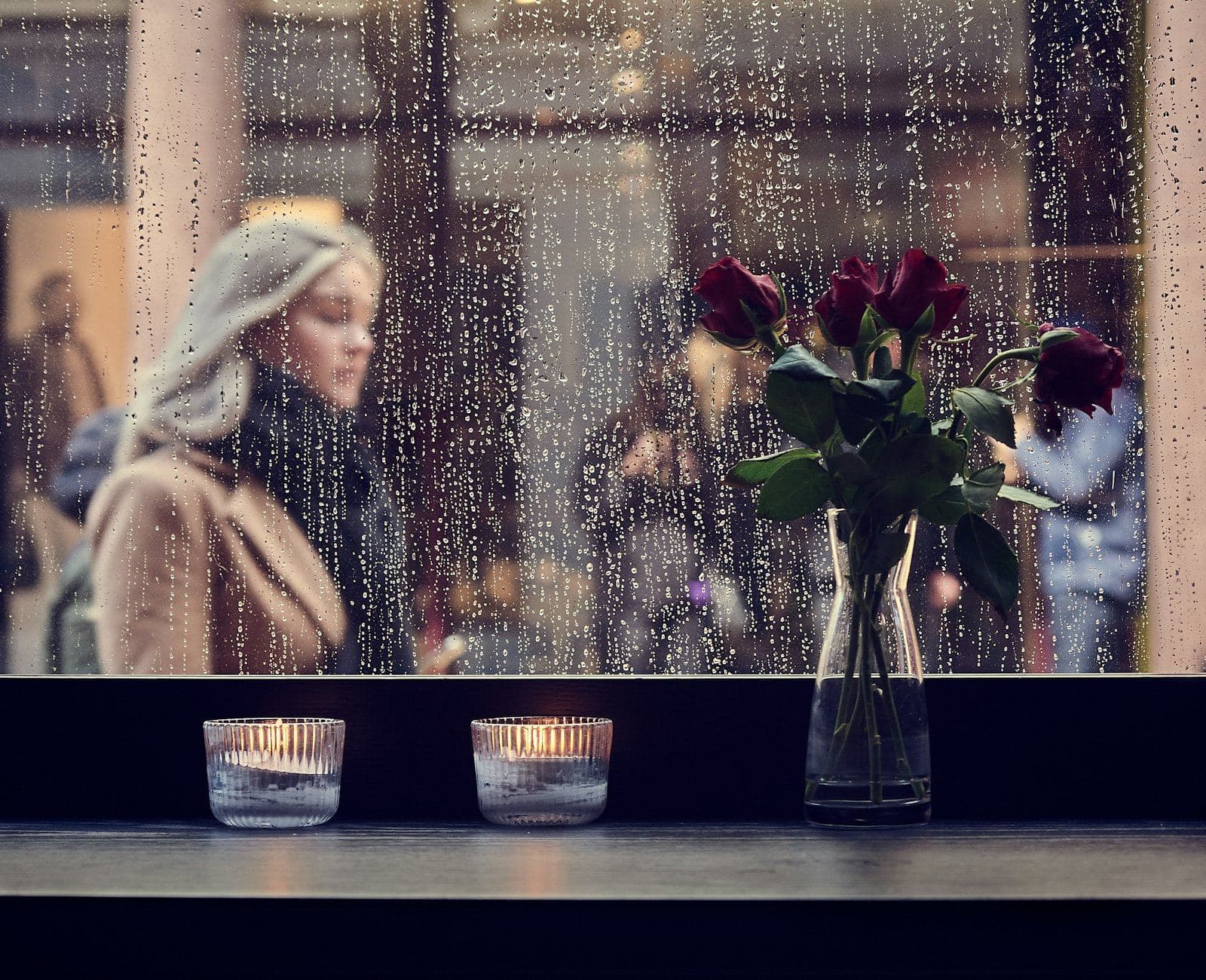 A woman looking out through a rain-streaked window