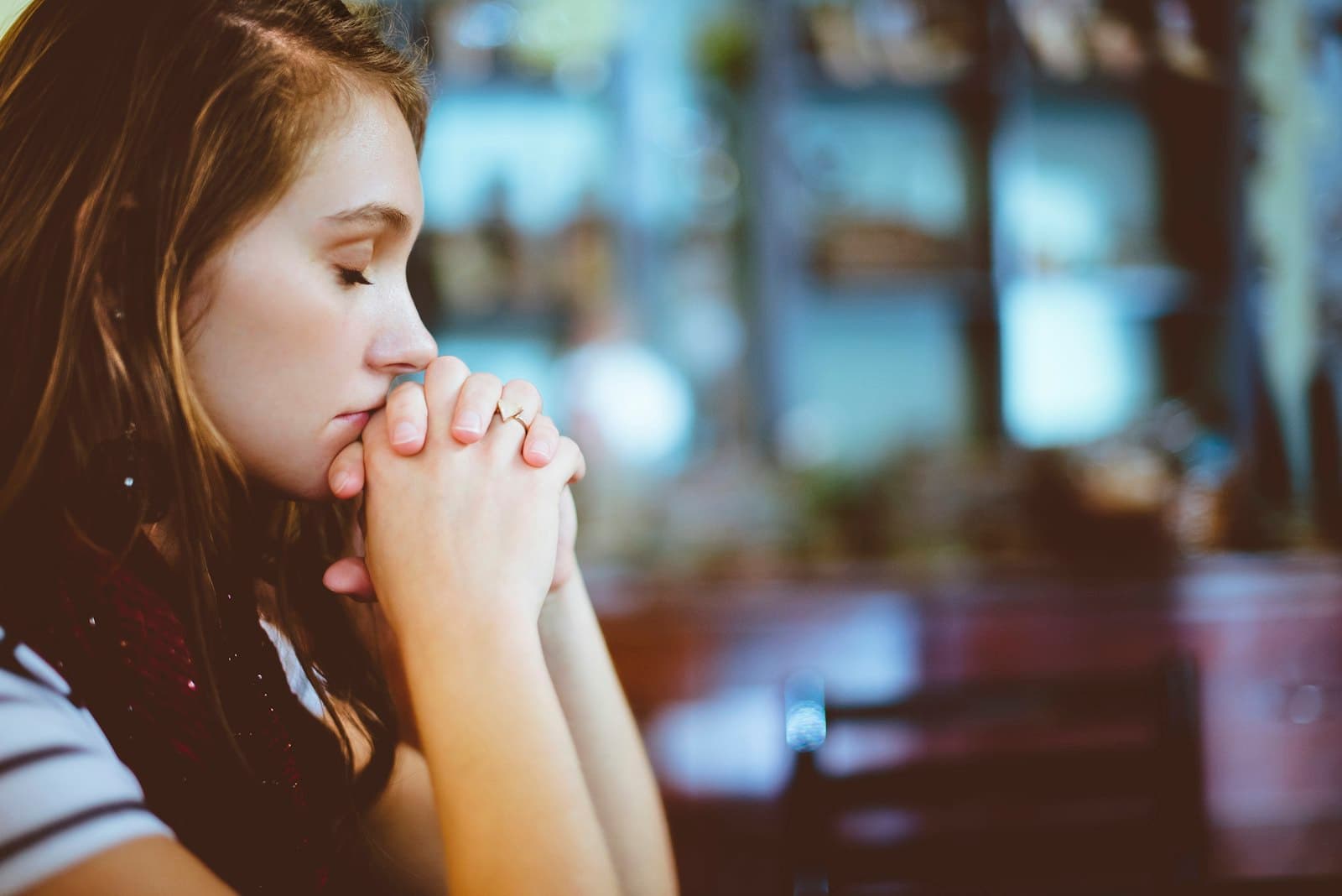 A young woman with her eyes closed and hands folded in prayer