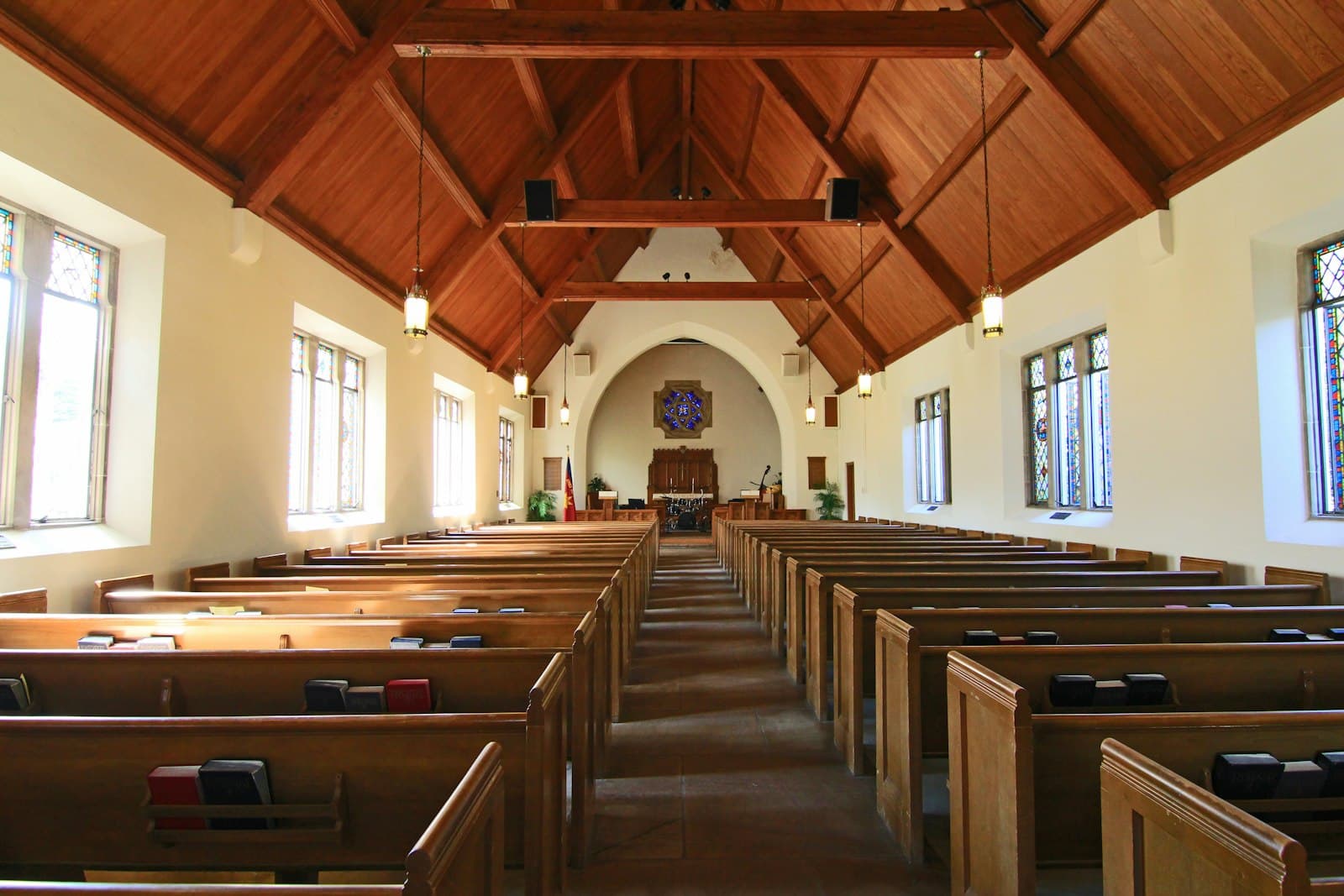The empty interior of a bright wooden-roofed church with rows of pews