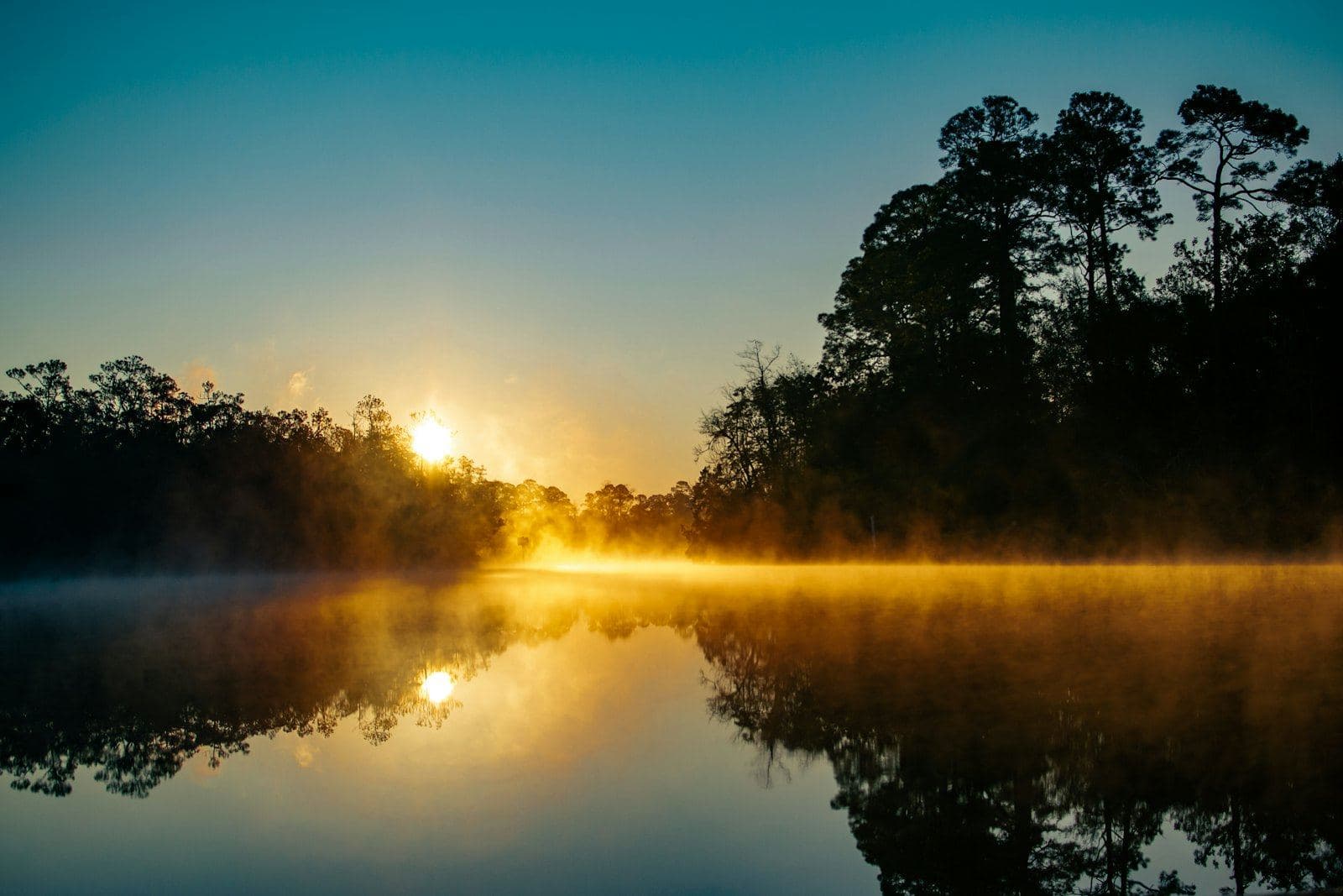 The sun rising over a quiet lake