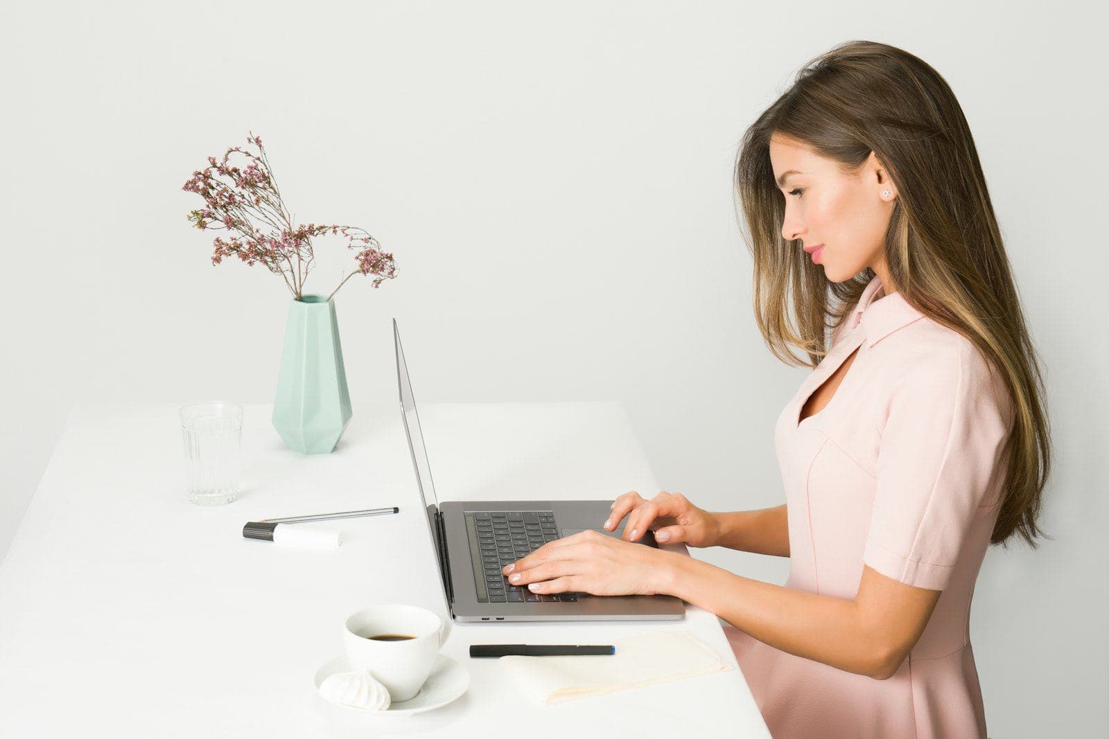 A woman reading on her laptop at a bright desk