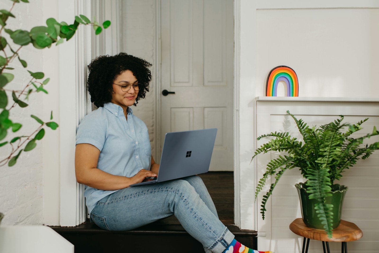 A woman on a video call from her laptop at home, surrounded by plants