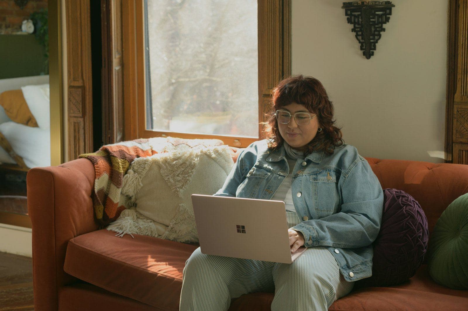 A woman on a sofa at home using her laptop