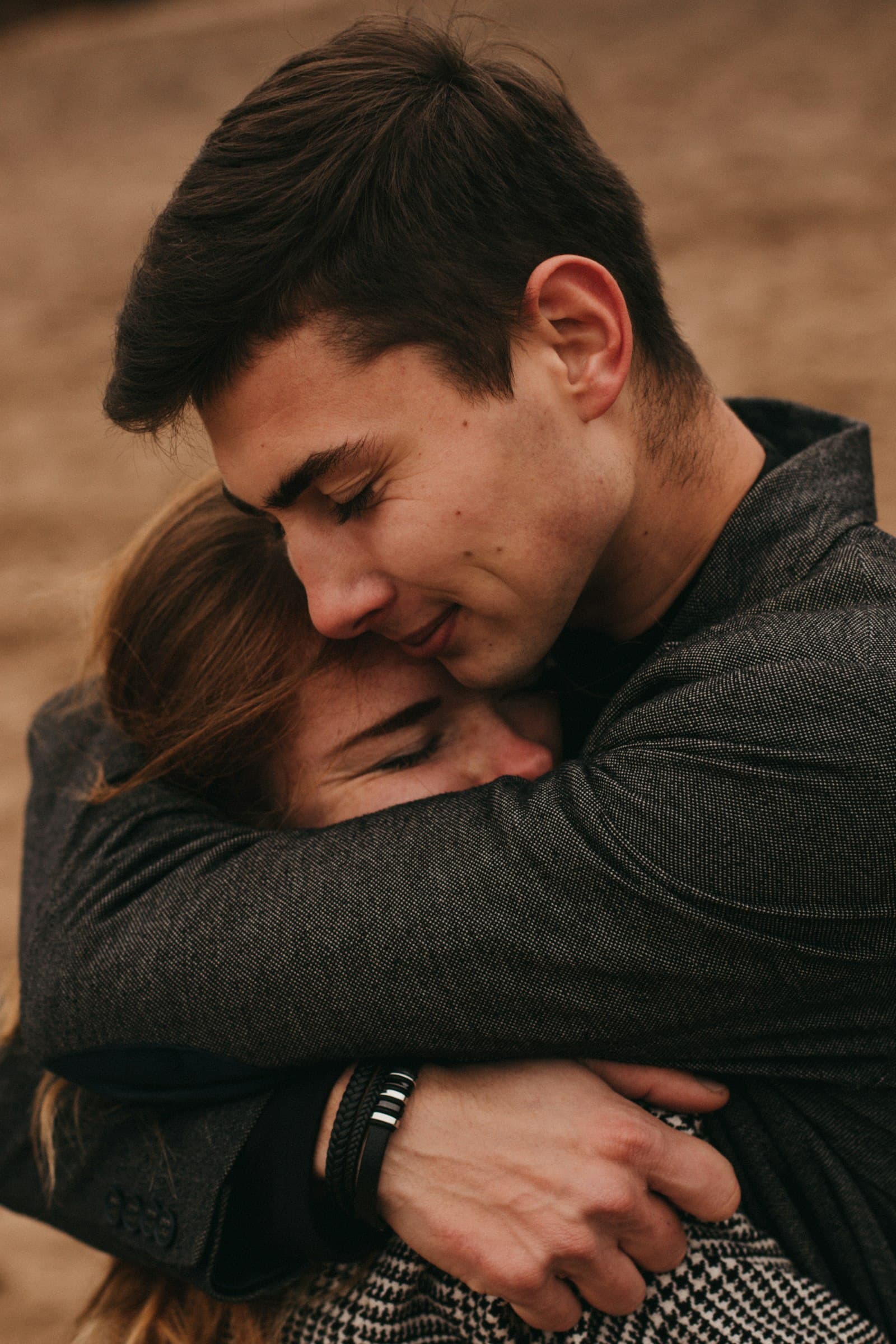 A young man holding a woman close in a quiet embrace, her eyes closed