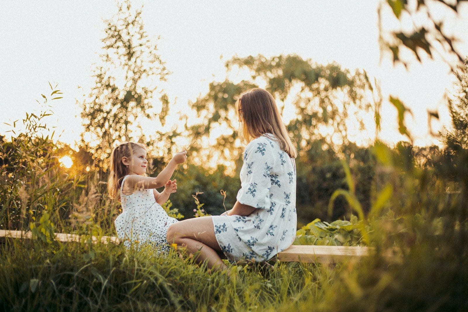 A mother and daughter sitting together in a sunny field