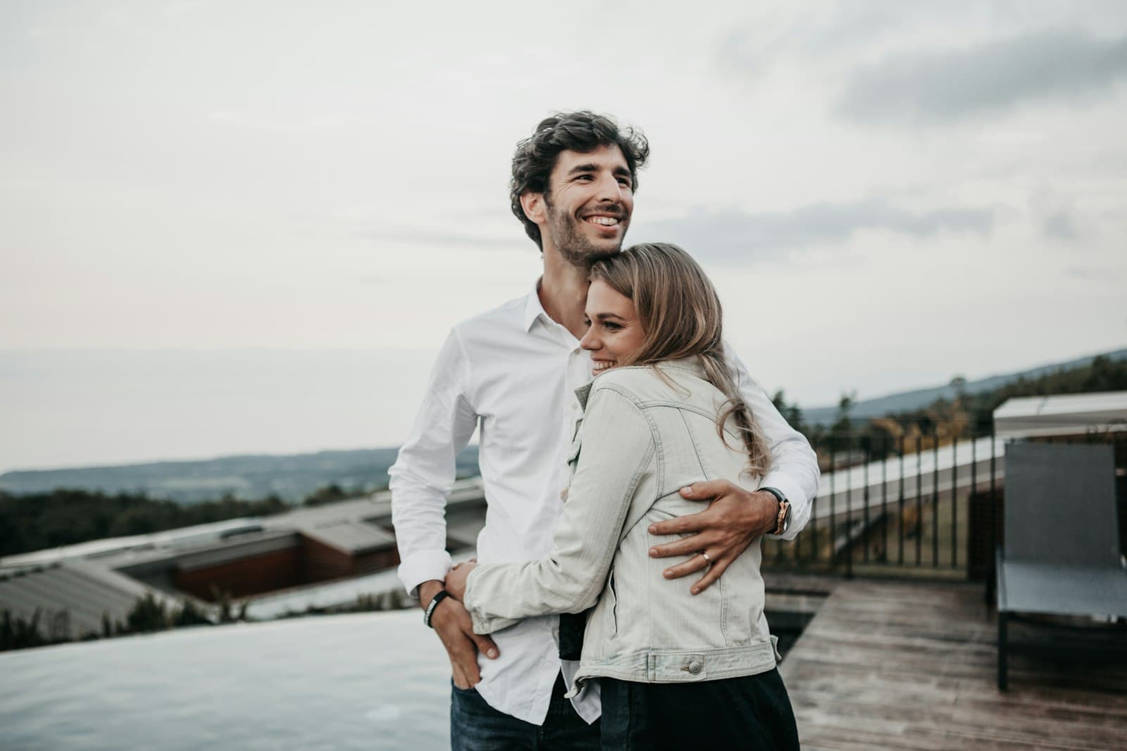 A smiling man and woman embracing on a terrace overlooking the countryside