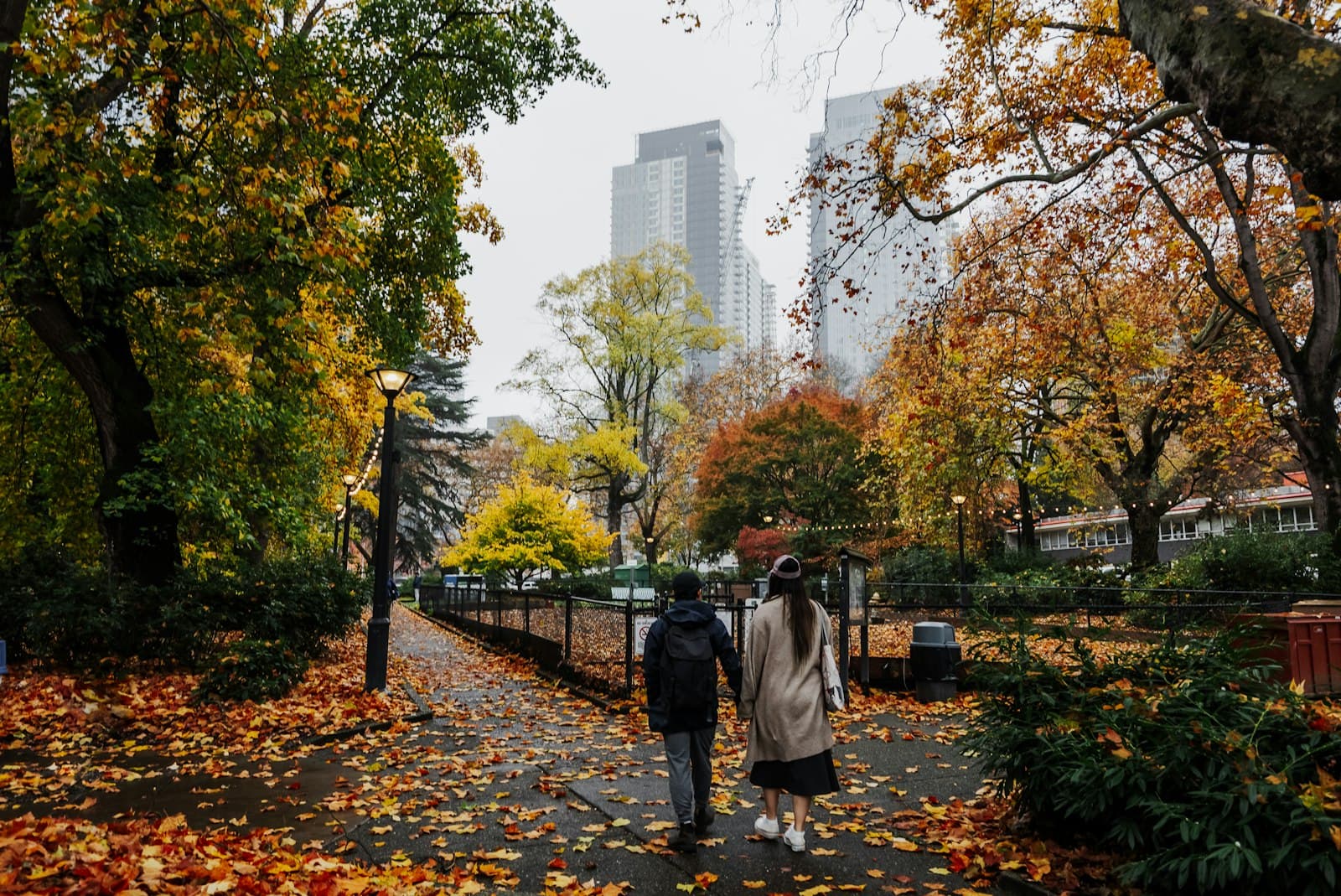 A couple walking side by side along a leafy park path in autumn