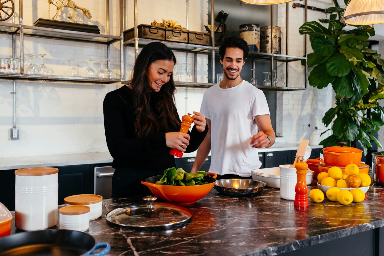 A smiling couple preparing vegetables together at a kitchen island