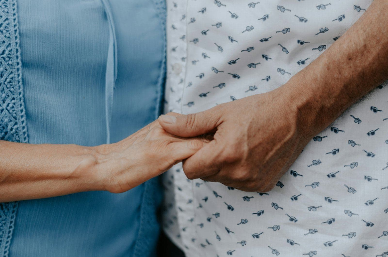 Two people holding hands in reassurance