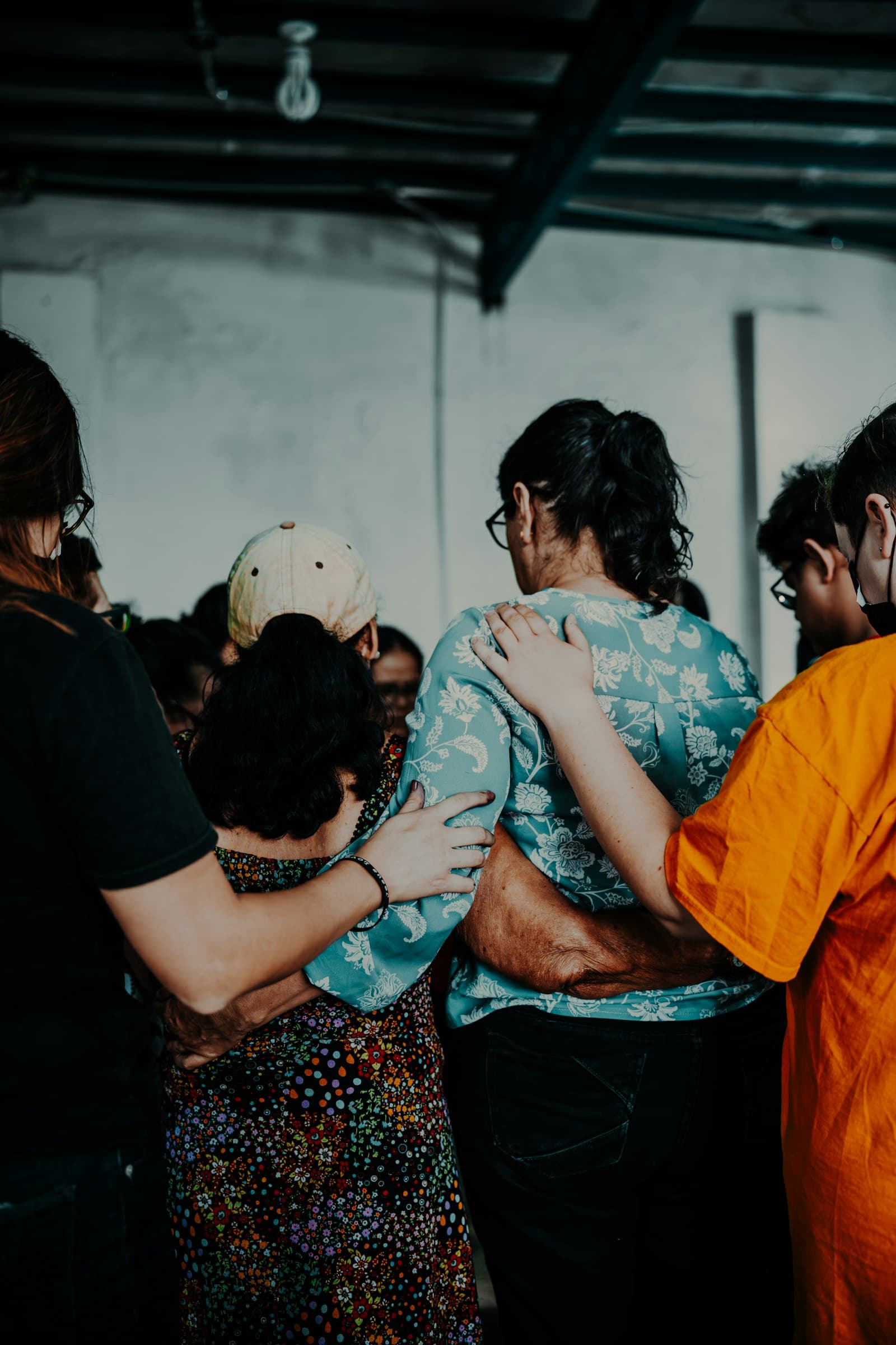 A small group of people standing with their arms around each other, seen from behind