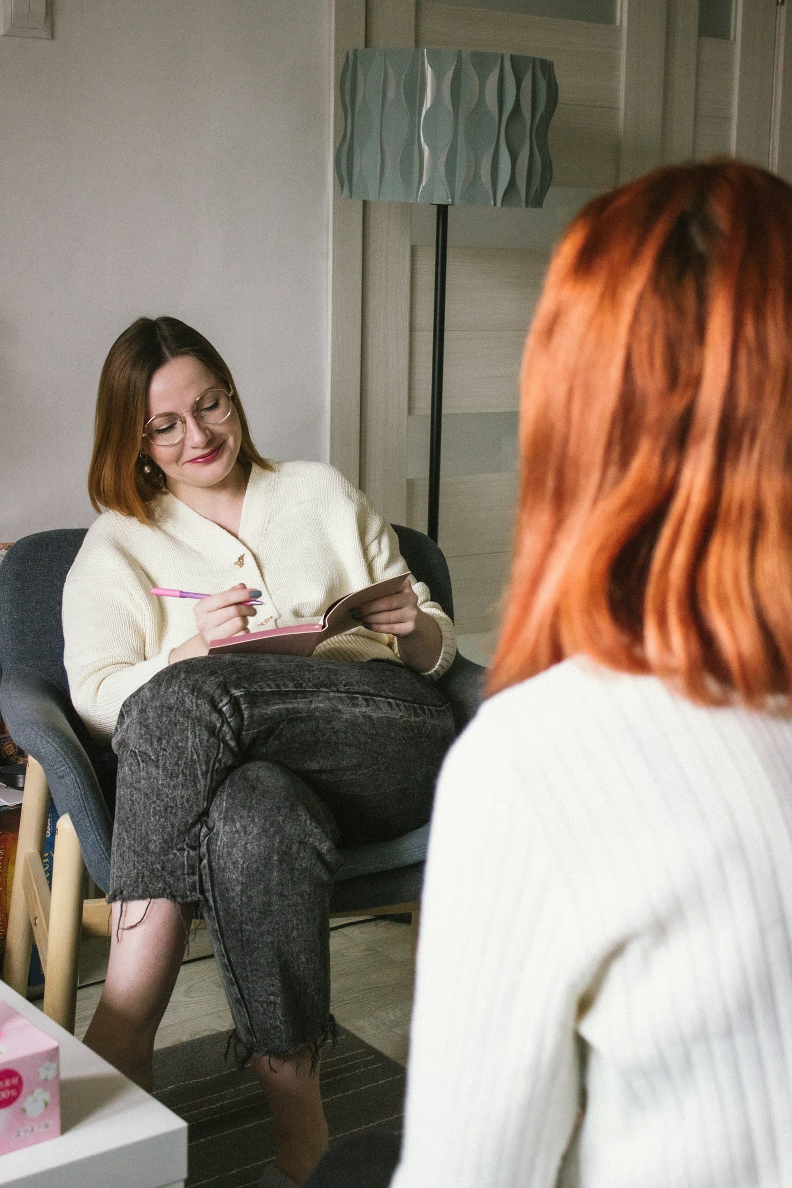 A therapist with a notebook listening to a client in a calm office