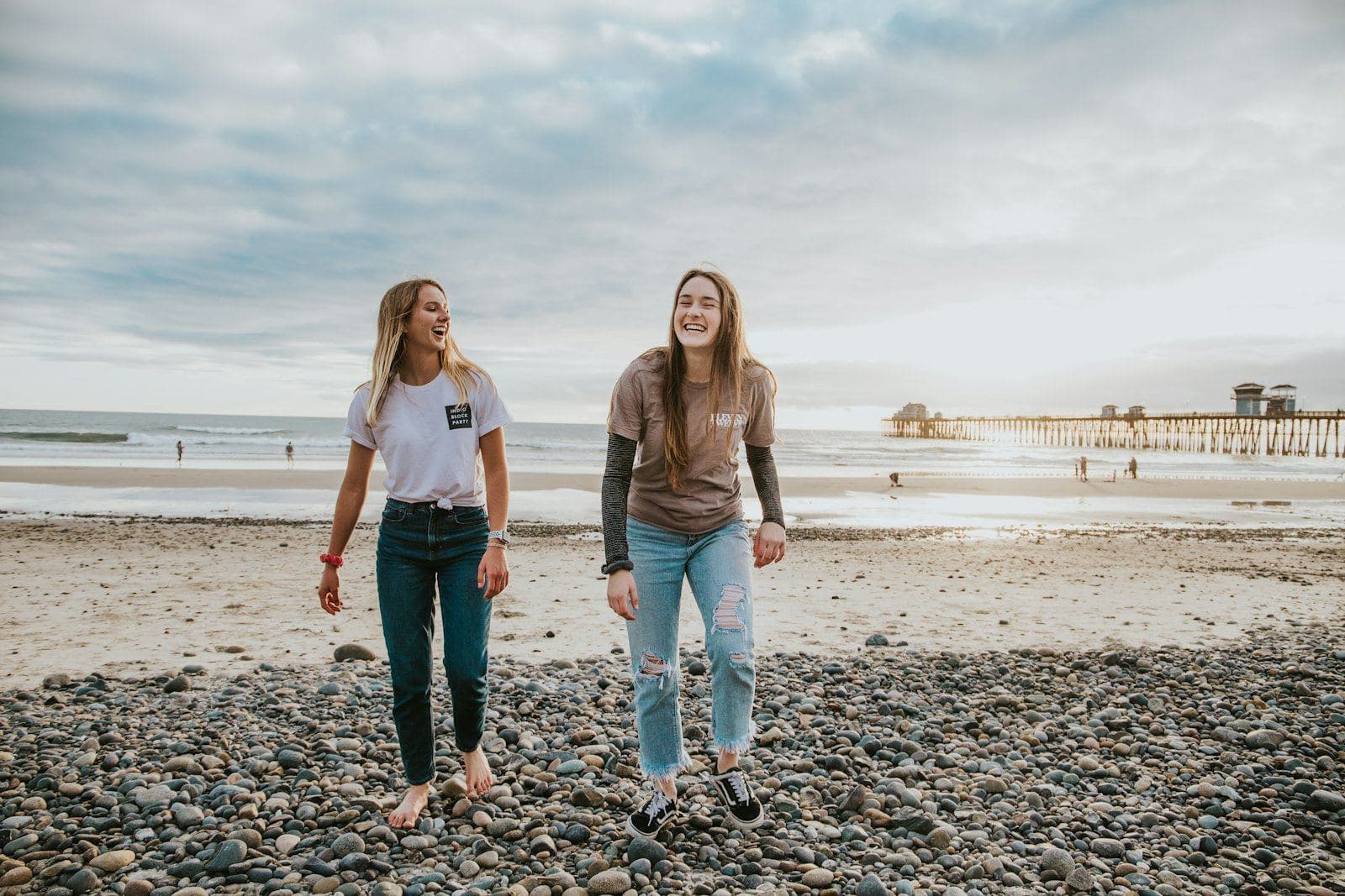 Two friends walking and laughing together on a beach