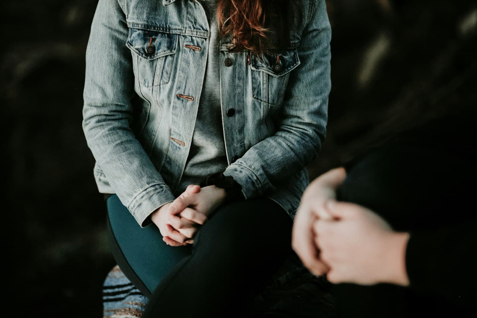 Two people sitting knee to knee in conversation, hands clasped