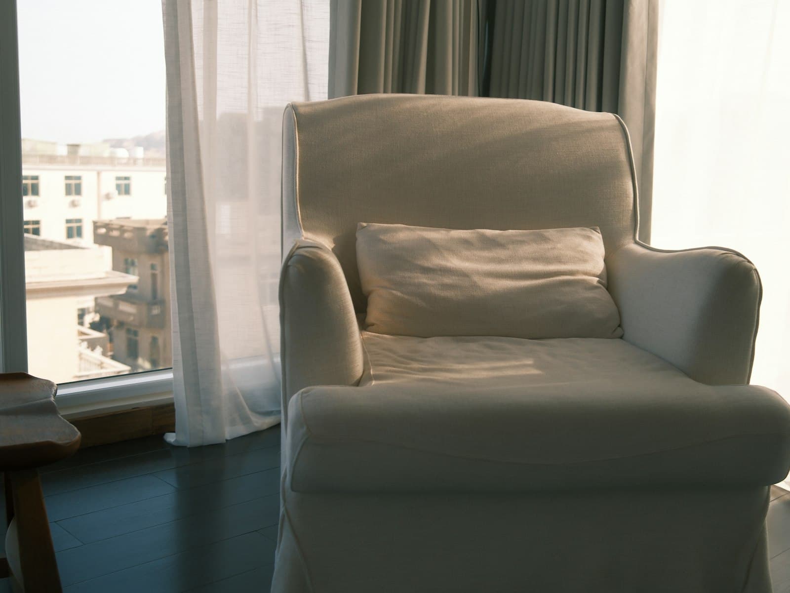 An empty armchair beside a curtained window