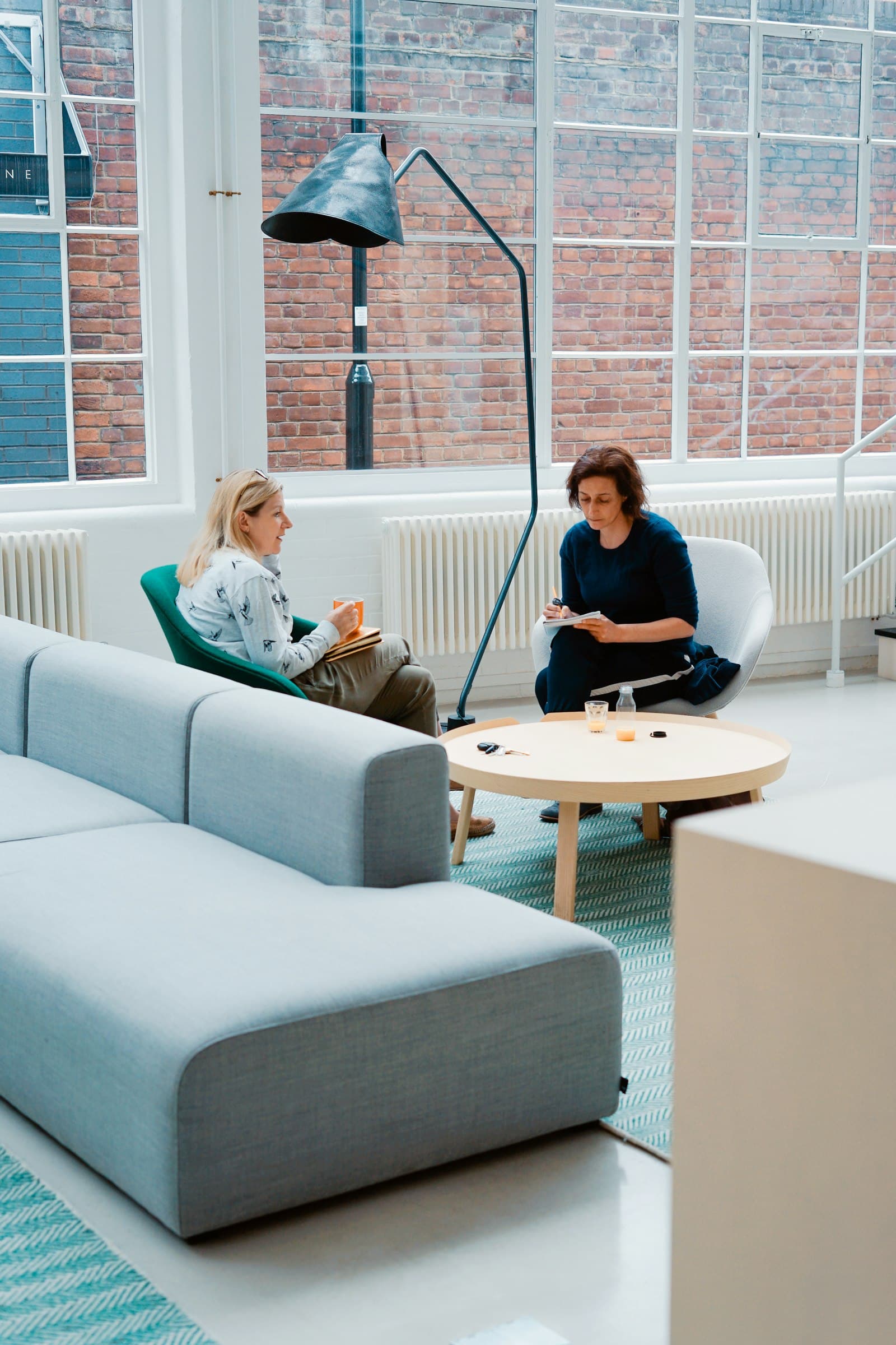 Two people seated in armchairs talking in a bright, modern consulting room